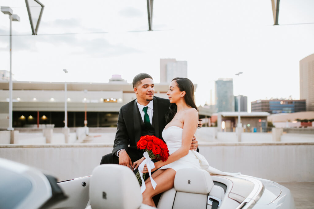 Bride and groom sit on back of rolls royce convertible for bridal session in arizona