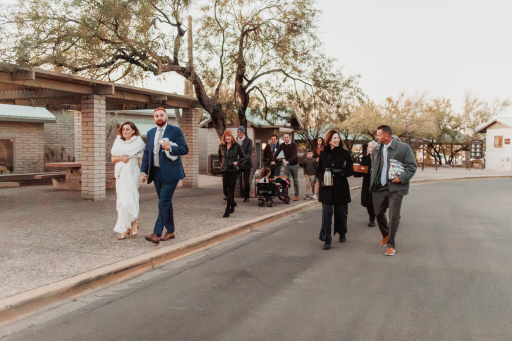 Bride and groom with guests walking to elopement ceremony site